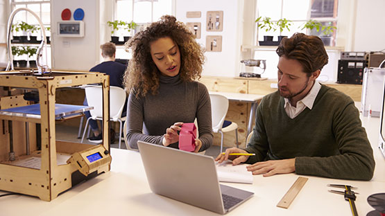 Man and woman in a design studio working on a laptop