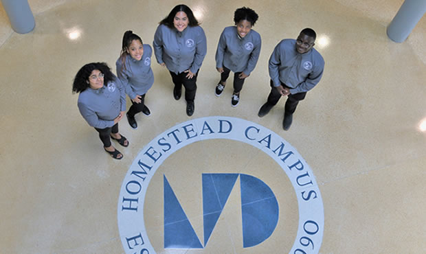 Group of SGA students pose next to the Homestead Campus floor insignia
