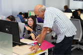 Student being assisted by tutor at computer courtyard