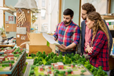 Three students review a proposed park layout at an office