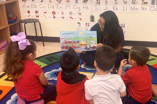 Teacher holding up a book to young children